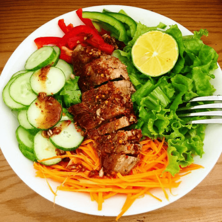 Thịt heo áp chảo, salad rau trộn kèm 1 lát chanh tươi.